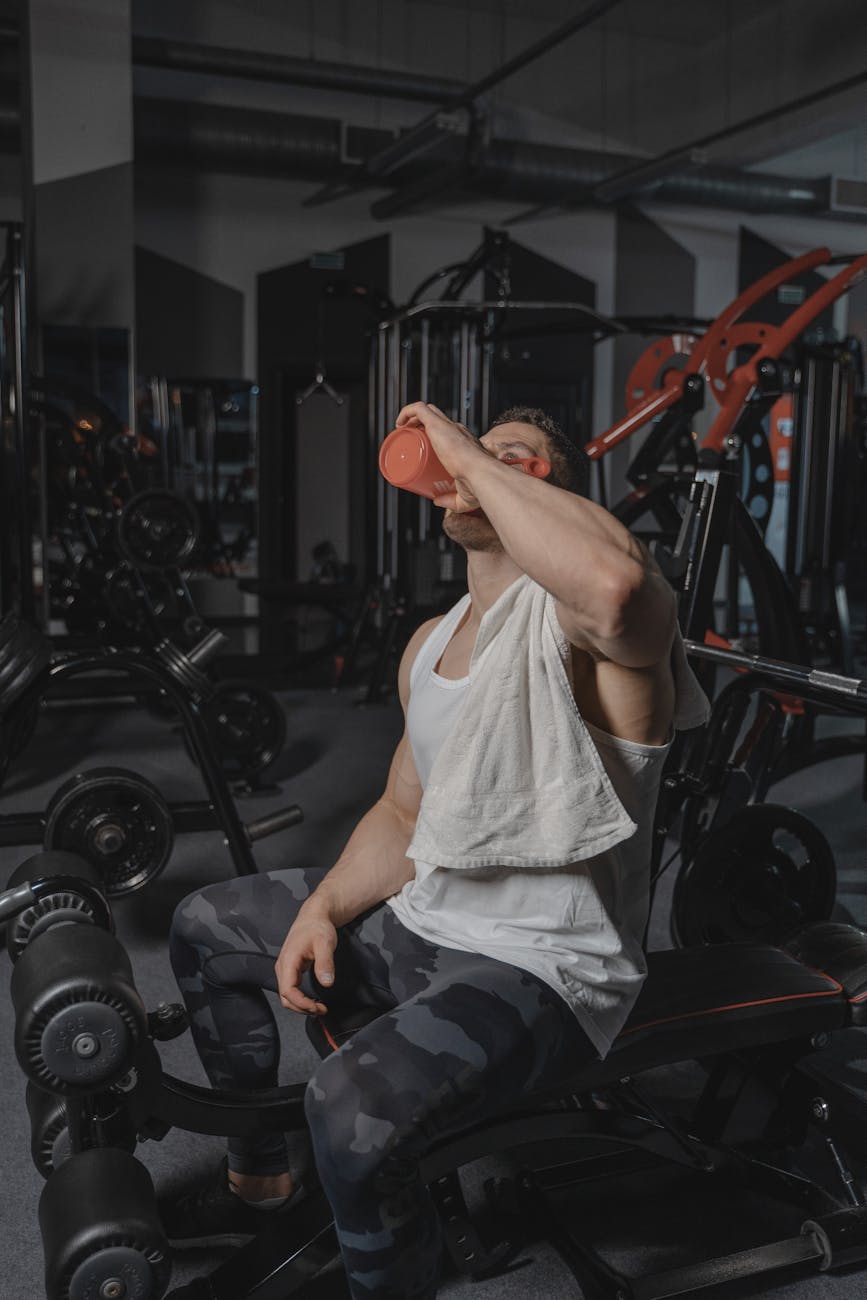 man in white tank top drinking water